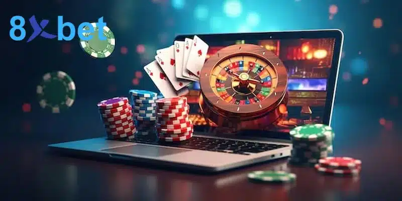 Laptop mở trò roulette bên cạnh các chồng chip cược nhiều màu và xấp lá bài