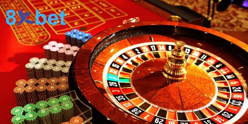 Vòng quay roulette châu Âu cạnh bàn cược đỏ và nhiều chồng chip màu