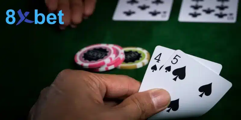 Người chơi cầm hai lá 4 bích và 5 bích bên cạnh chip cược trên bàn bài