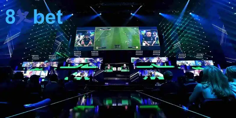 Sân khấu esports ánh đèn xanh với màn hình lớn chiếu trận game bóng đá và khán giả theo dõi