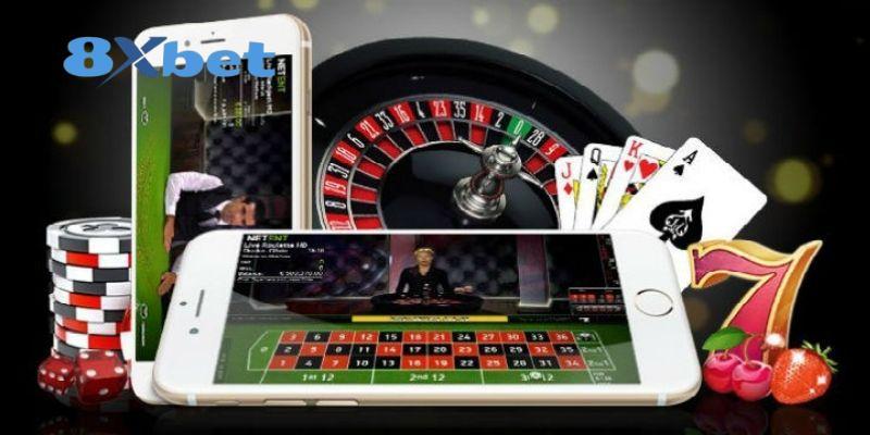 Hai điện thoại mở bàn roulette trực tiếp cạnh vòng quay roulette, bộ bài và chồng chip