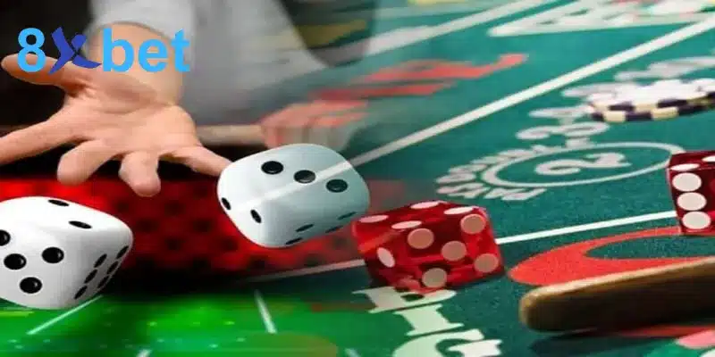 Bàn tay tung xúc xắc trắng và đỏ trên mặt bàn casino màu xanh