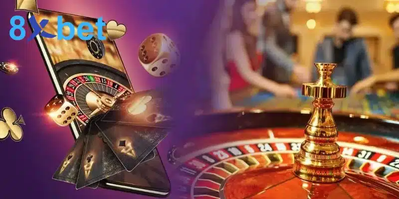 Bàn chơi casino với vòng quay roulette bên cạnh điện thoại và lá bài thể hiện các tựa game 8XBET casino