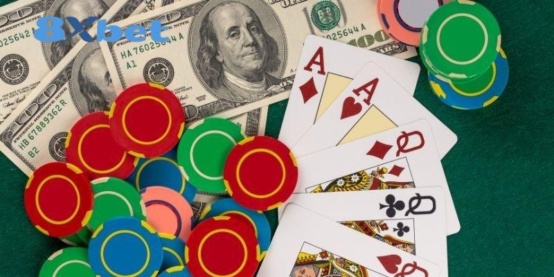 Chip casino nhiều màu, tiền giấy và bộ bài với logo 8XBET trên nền bàn xanh